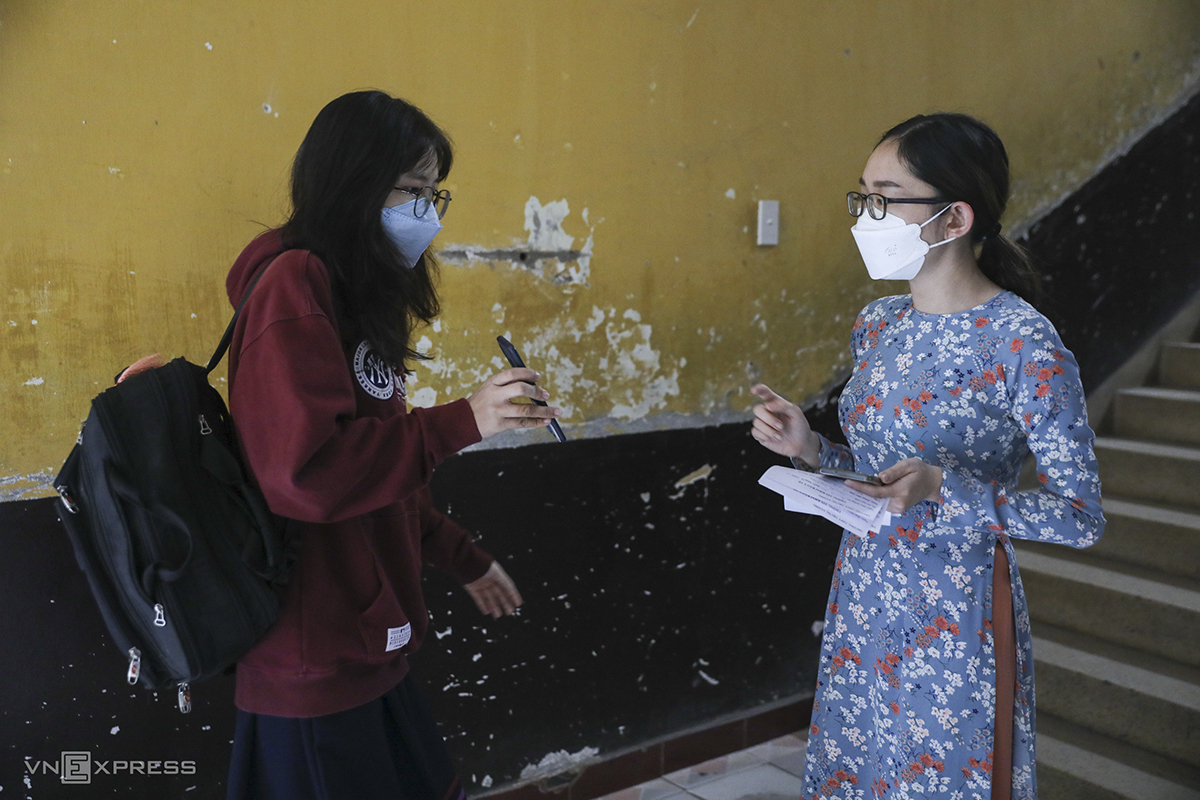 A teacher checks a health declaration form before letting a student in class.