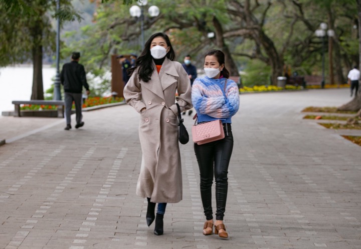 People huddled in the cold while walking in Hoan Kiem Lake.