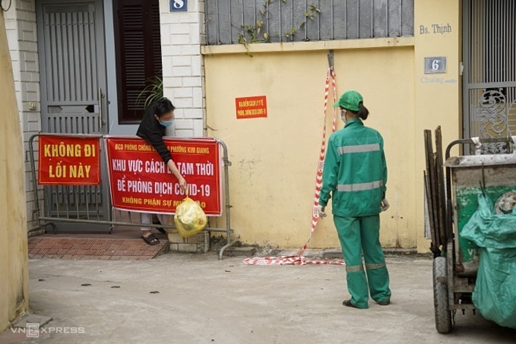 A garbage collector waits to pick trash from a Covid patients family n Kim Giang Ward, Thanh Xuan District, December 2021. Photo by VnExpress/Pham Chieu