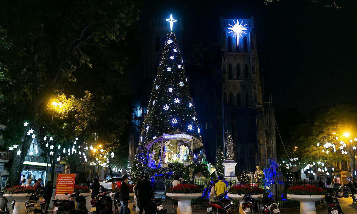 A giant Christmas tree and nativity scene in front of the St. Josephs Cathedral. The cathedral of the Roman Catholic Archdiocese of Hanoi for the nearly four million Catholics is still under construction.  Police officers frequently patrol the area to remind people to comply with pandemic prevention measures as Hanoi has in recent days led in the number of daily new cases in the country.Hanoi authorities earlier urged people to limit large gatherings during the Christmas holiday to ensure pandemic prevention measures..