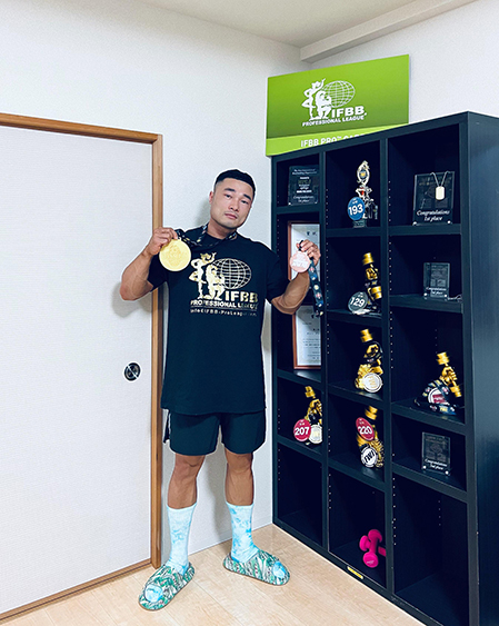 Son next to the bodybuilding awards he received in Japan. Photo courtesy of Son