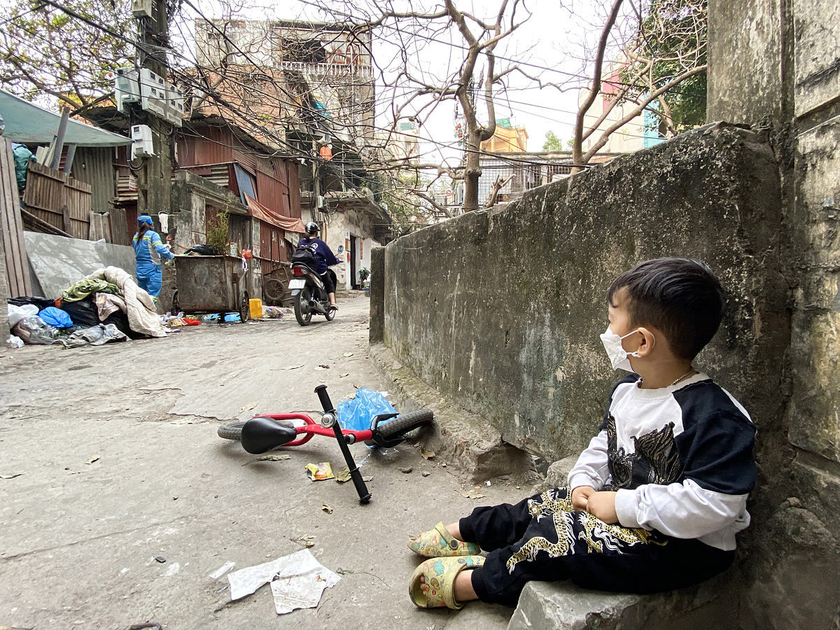 Thoc sits on the side of the road waiting for his mother to collect garbage on Dec. 25, 2021. Photo by VnExpress/Quynh Nguyen