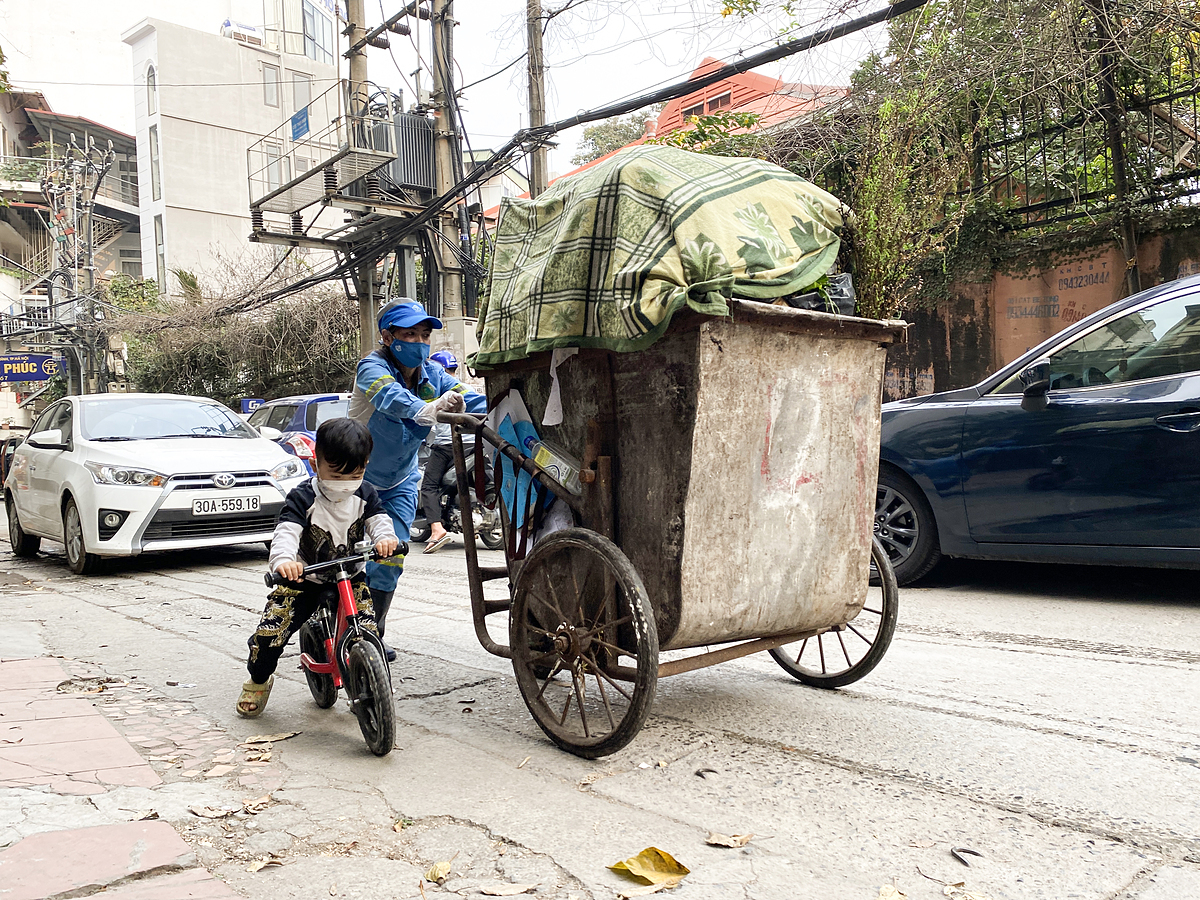 Pham Thi Lan pushs a garbage truck to a collection point on Kim Ma Street, with her son riding a bicycle next to her, on Dec. 25, 2021. Photo by VnExpress/Quynh Nguyen