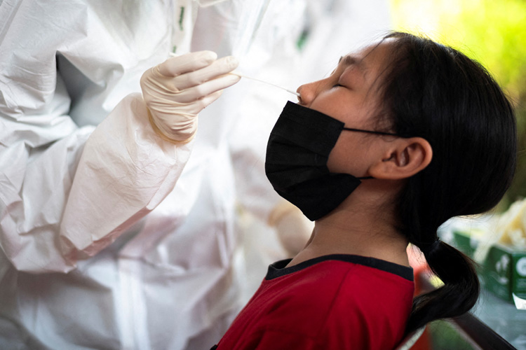 A health worker from Zendai organisation in personal protective equipment (PPE) takes a swab sample from a girl for a rapid antigen test amid the coronavirus disease (COVID-19) outbreak, in Bangkok, Thailand, January 5, 2022. Photo by Reuters