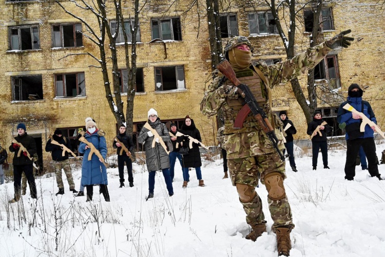 A military instructor teaches civilians holding wooden replicas of Kalashnikov rifles, during a training session at an abandoned factory in the Ukrainian capital of Kyiv on January 30, 2022. As fears grow of a potential invasion by Russian troops massed on Ukraines border, within the framework of the training there were classes on tactics, paramedics, training on the obstacle course. The training is conducted by instructors with combat experience, members of the public initiative Total Resistance. Photo by AFP