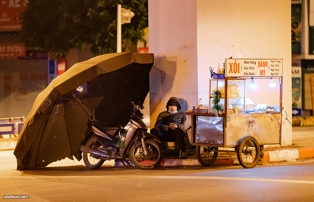 A pushcart sticky rice and sandwich vendor uses a large outdoor umbrella as a shield. The bitter cold in the north will last until February 24, weather experts have said. Temperatures in the northern delta are forecast at 8-11 degrees Celsius, with the mercury falling even further in the mountains to 3-6 degrees Celsius.