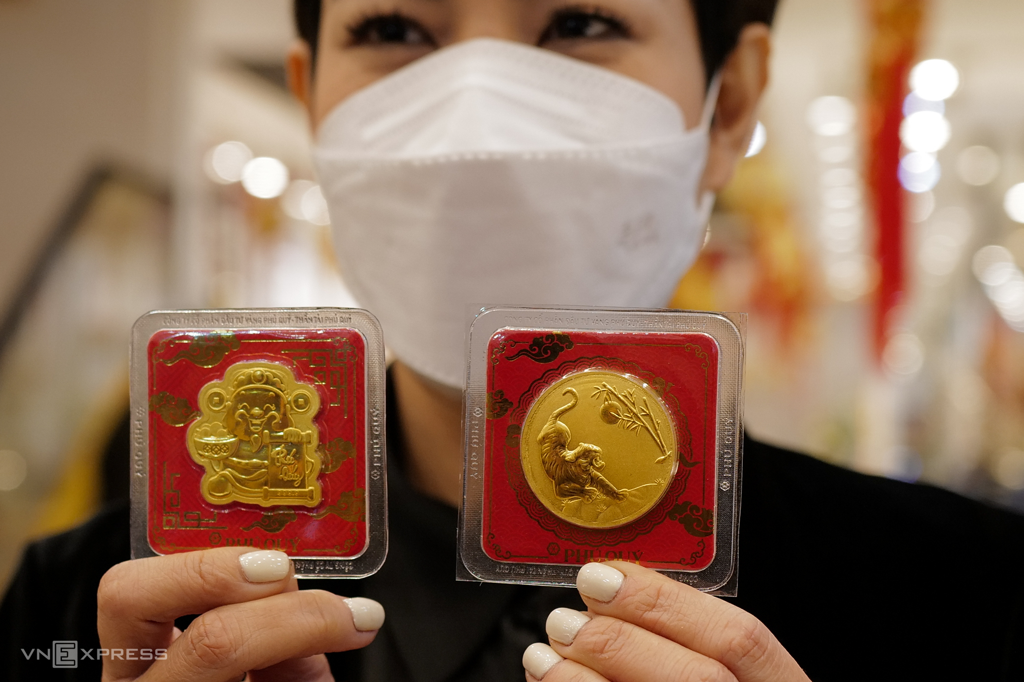 A staff member displays two pieces of gold, with one decorated with the God of Wealth and the other a tiger, the zodiac animal of the 2022 lunar year.
