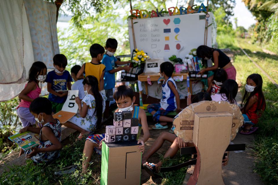 Children read and learn through the makeshift trolley which serves as a mobile library, near the railroad, in Tagkawayan, Quezon Province, Philippines, February 15, 2022. Picture taken February 15, 2022. Photo by Reuters/Lisa Marie David