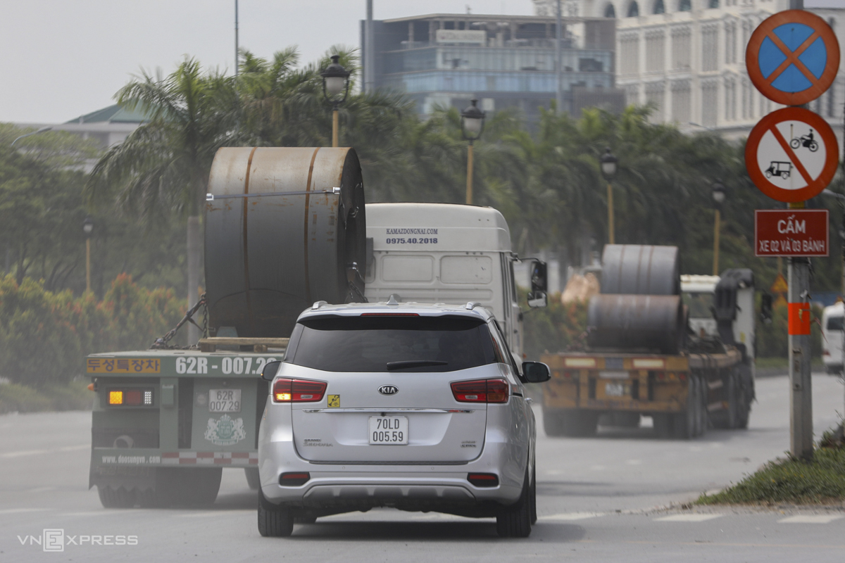 Tractor-trailers with steel coils head to the western gateway to the city on Nguyen Van Linh Street