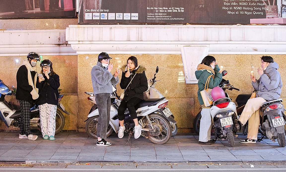 People eat ice cream on the sidewalk in Hanoi on Feb. 22, 2022. Photo by VnExpress/Tung Dinh