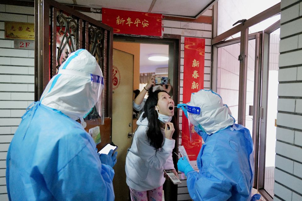 A worker in a protective suit collects a swab from a resident at a residential compound under lockdown, following the coronavirus disease (COVID-19) outbreak in Shenzhen, Guangdong province, China March 14, 2022. Photo by Reuters