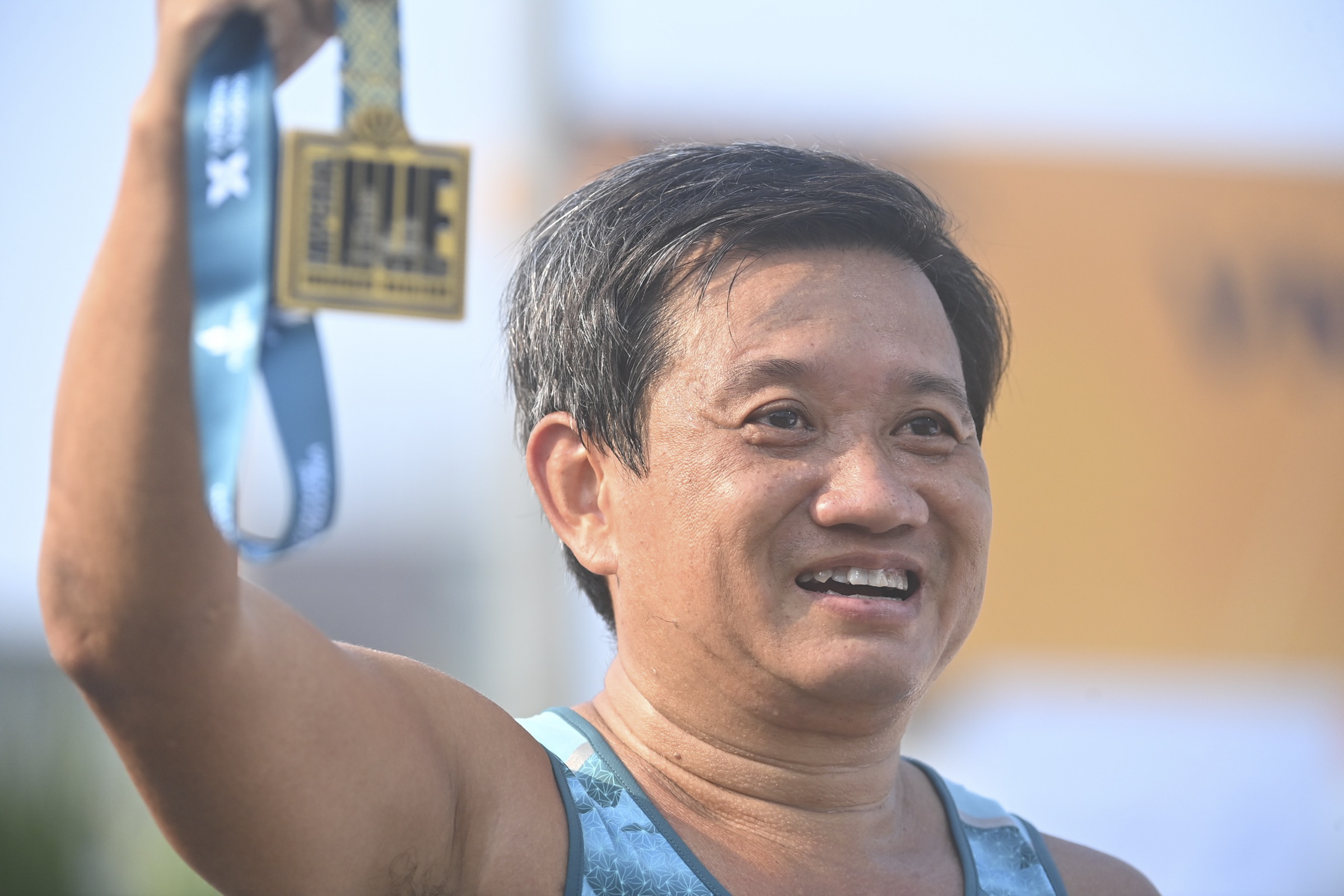 Doan Ngoc Hai wears a proud smile as he shows off the medal that confirms he has finished the full marathon - 42km.
