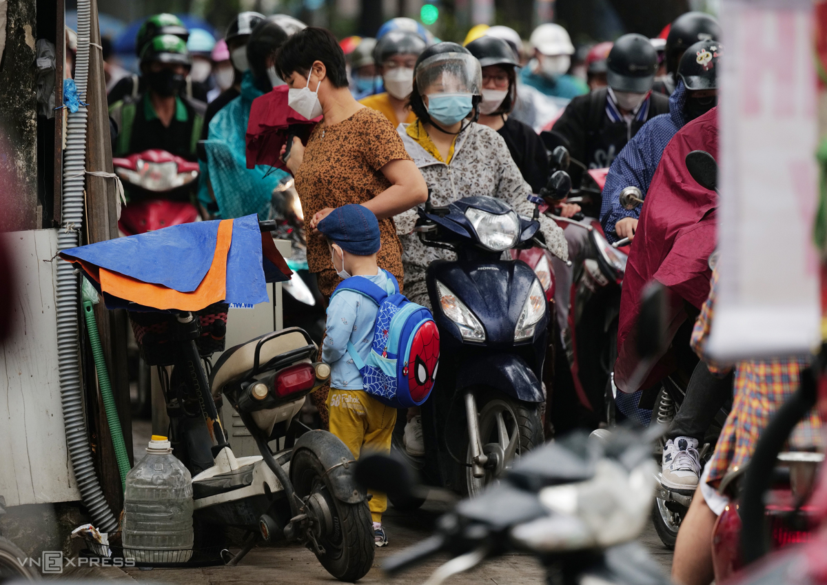A mother walking her child to school struggle to navigate through the sea of motorbikes overflowing the sidewalk on Nguyen Trai Street.