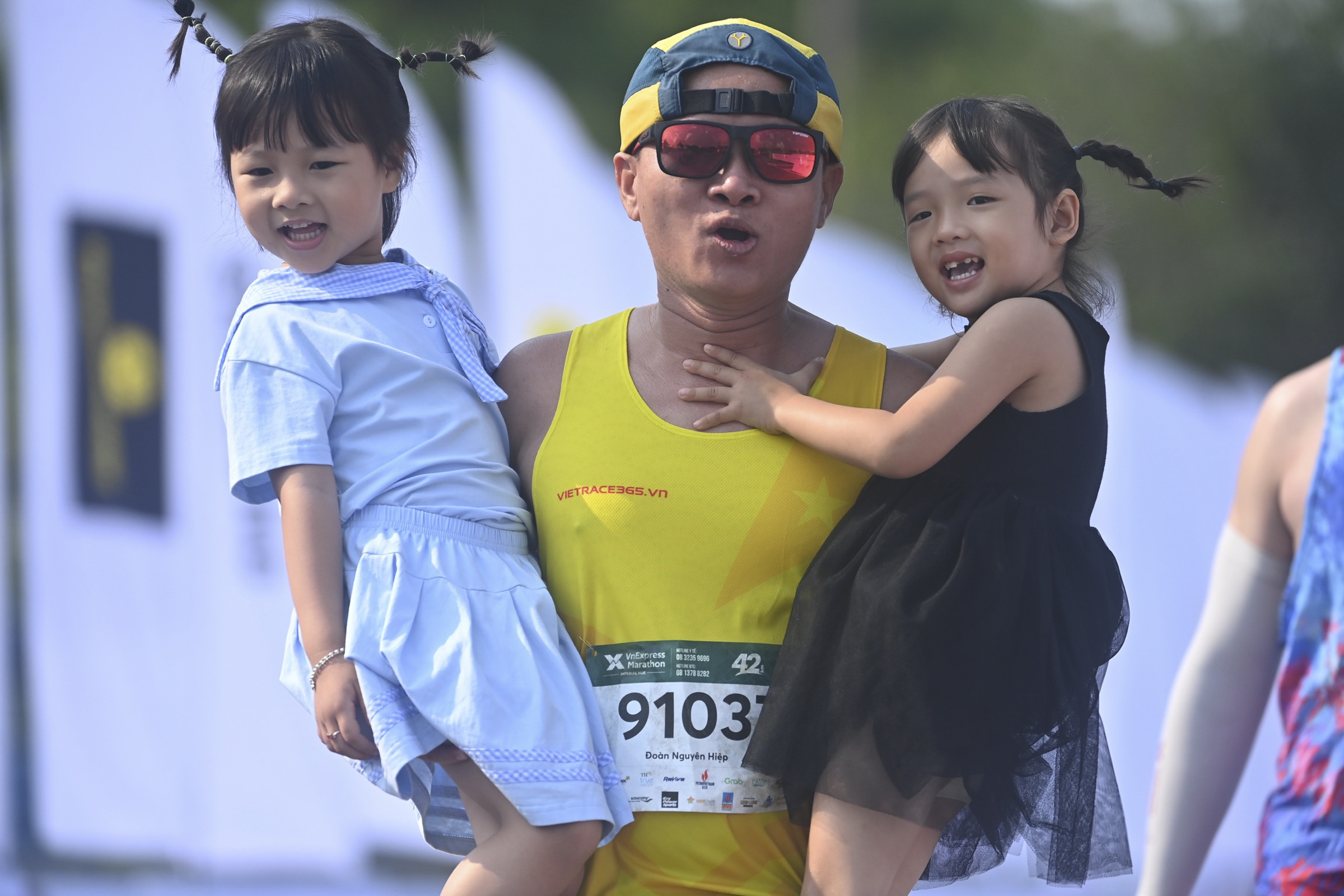 A man picks his daughters up after finishing his 42km run.