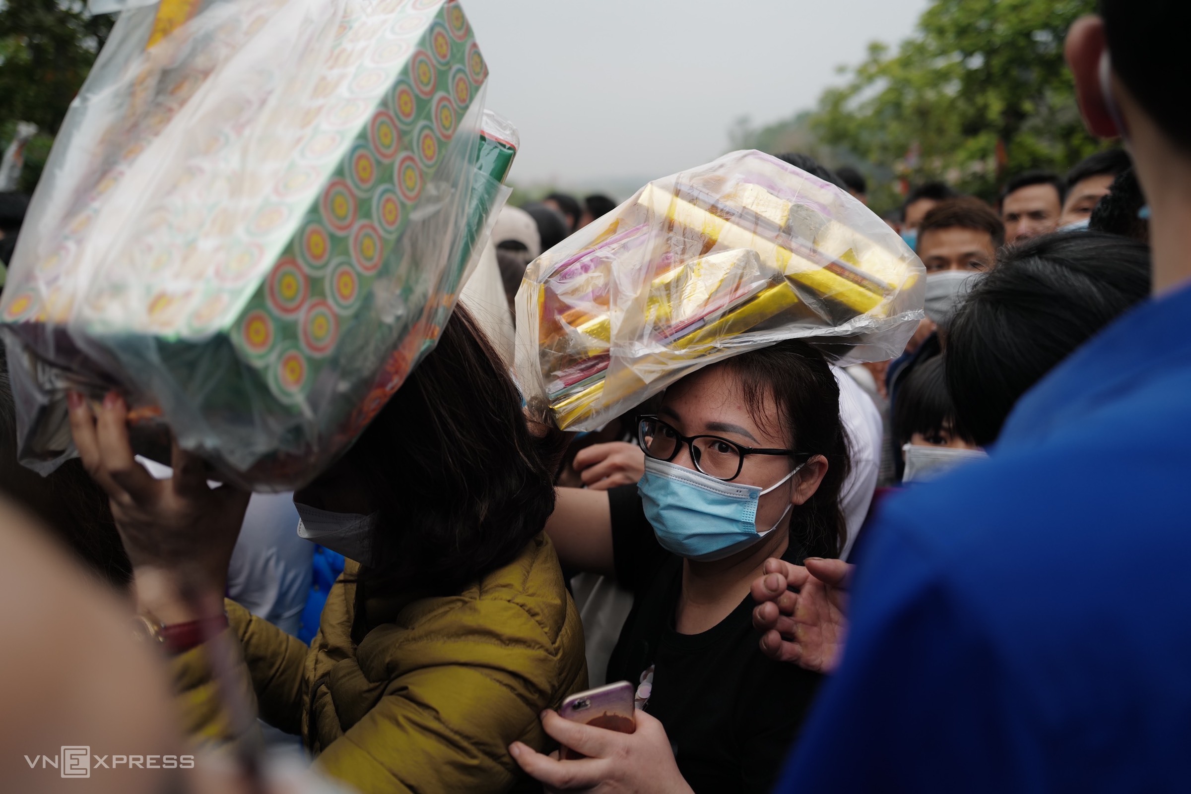 Two women carry offerings on their heads as they tried to weave their way through the crowd. Many people set up camps to stay overnight inside the temple area or at the foot of Nghia Linh Mountain for the main ceremony that takes place Sunday.