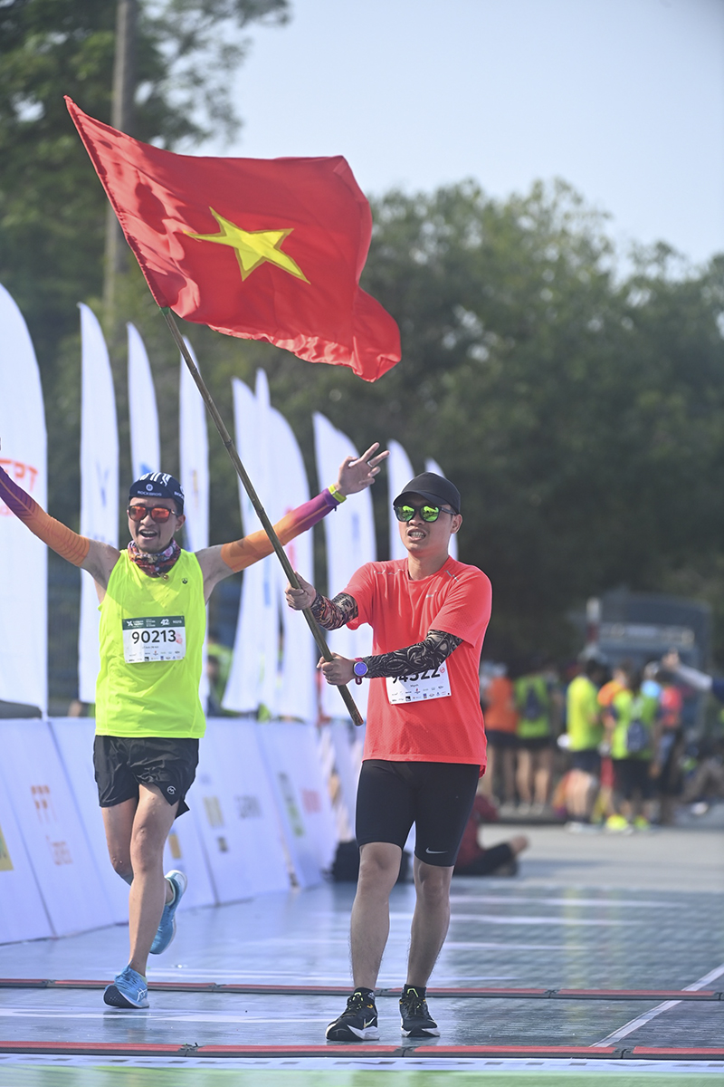 A man raises the national flag at the finish line.