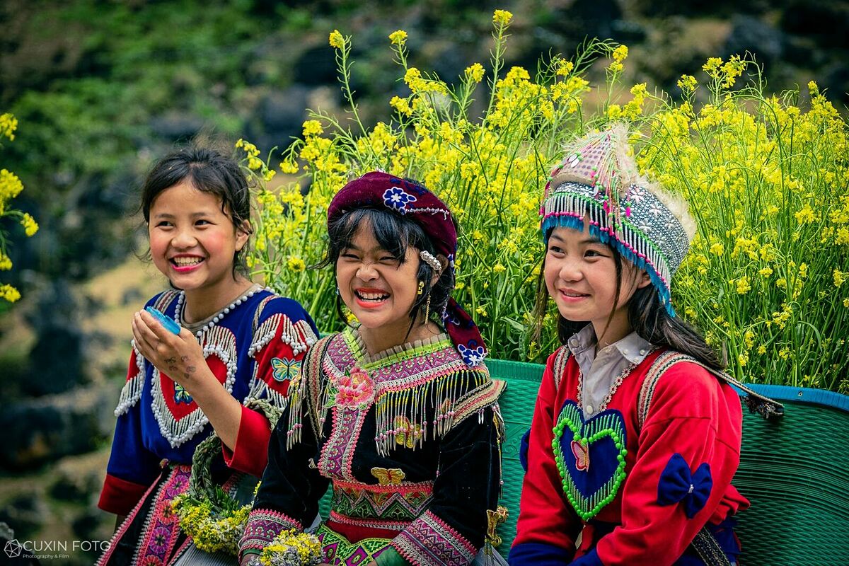 Children smile with flowers on their back rattan baskets in Ha Giang Province. Photo by Pham Xuan Quy.