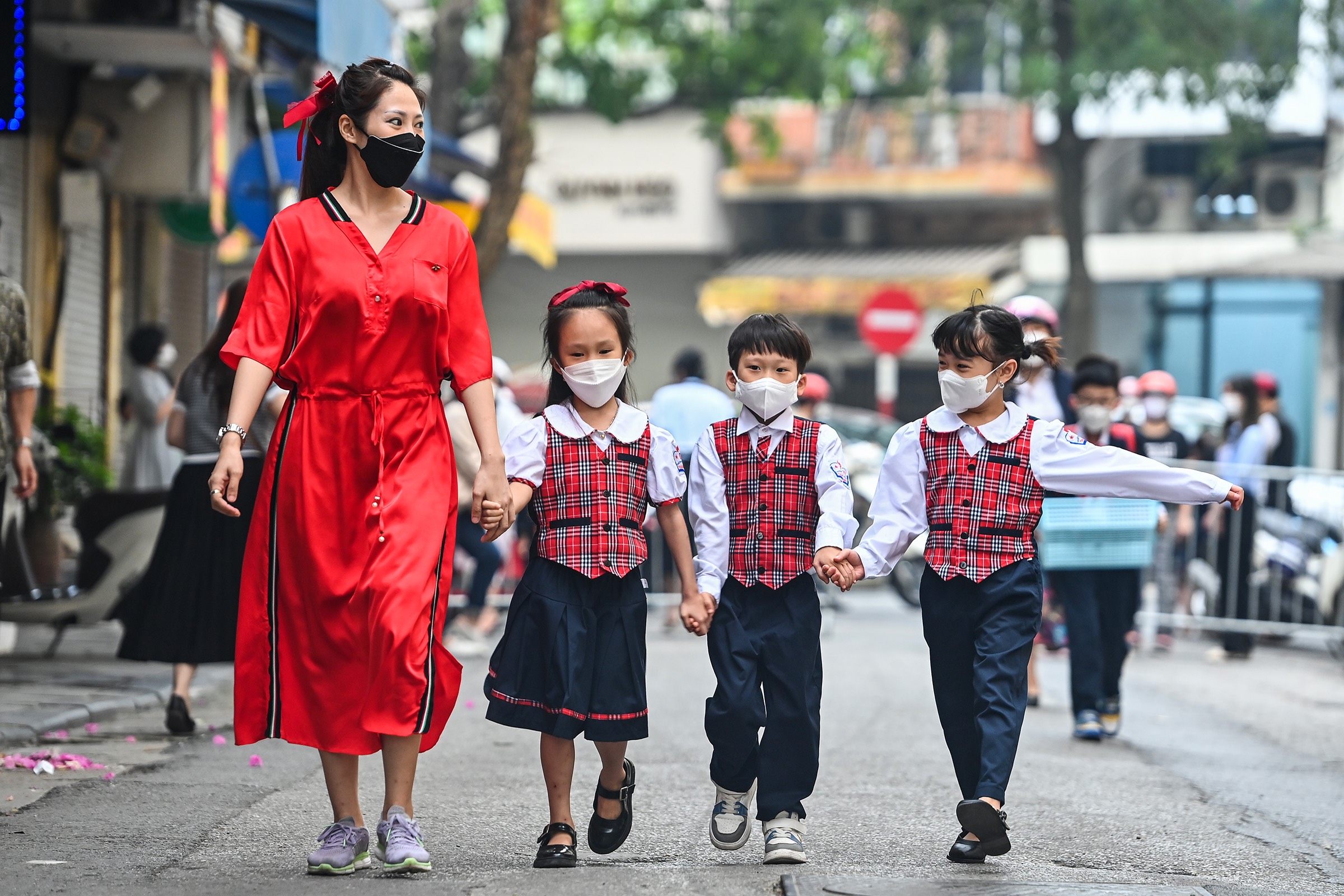 A woman takes three primary grade kids to school in Hanoi, April 6, 2022. Photo by VnExpress/Giang Huy