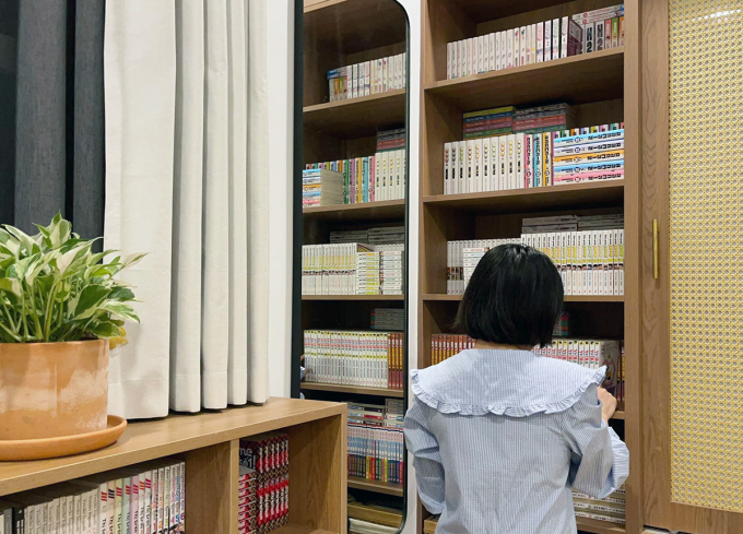 Huong Mai stands next to her bookshelves with over 3,000 comic books. Photo by VnExpress/Minh Trang